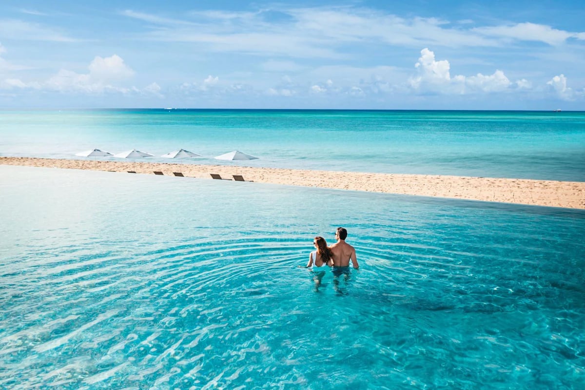 couple in pool looking out to beach and sea